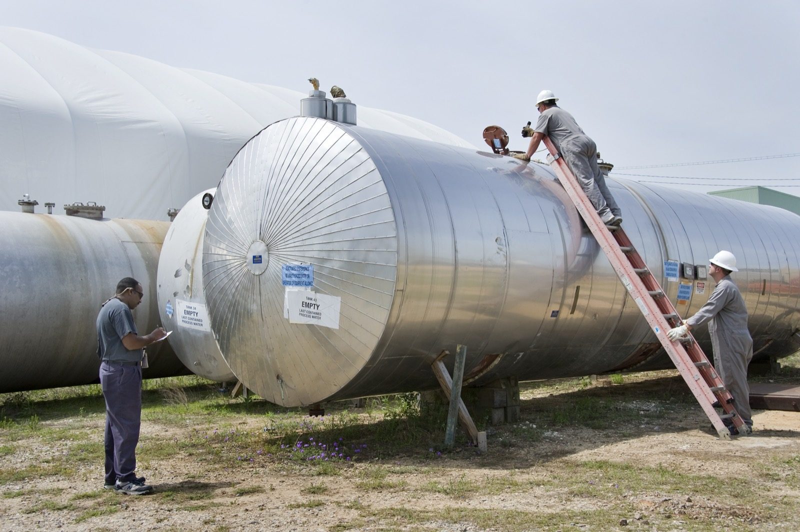 Workers inspecting bulk chemical storage tanks at a fertiliser and chemical site